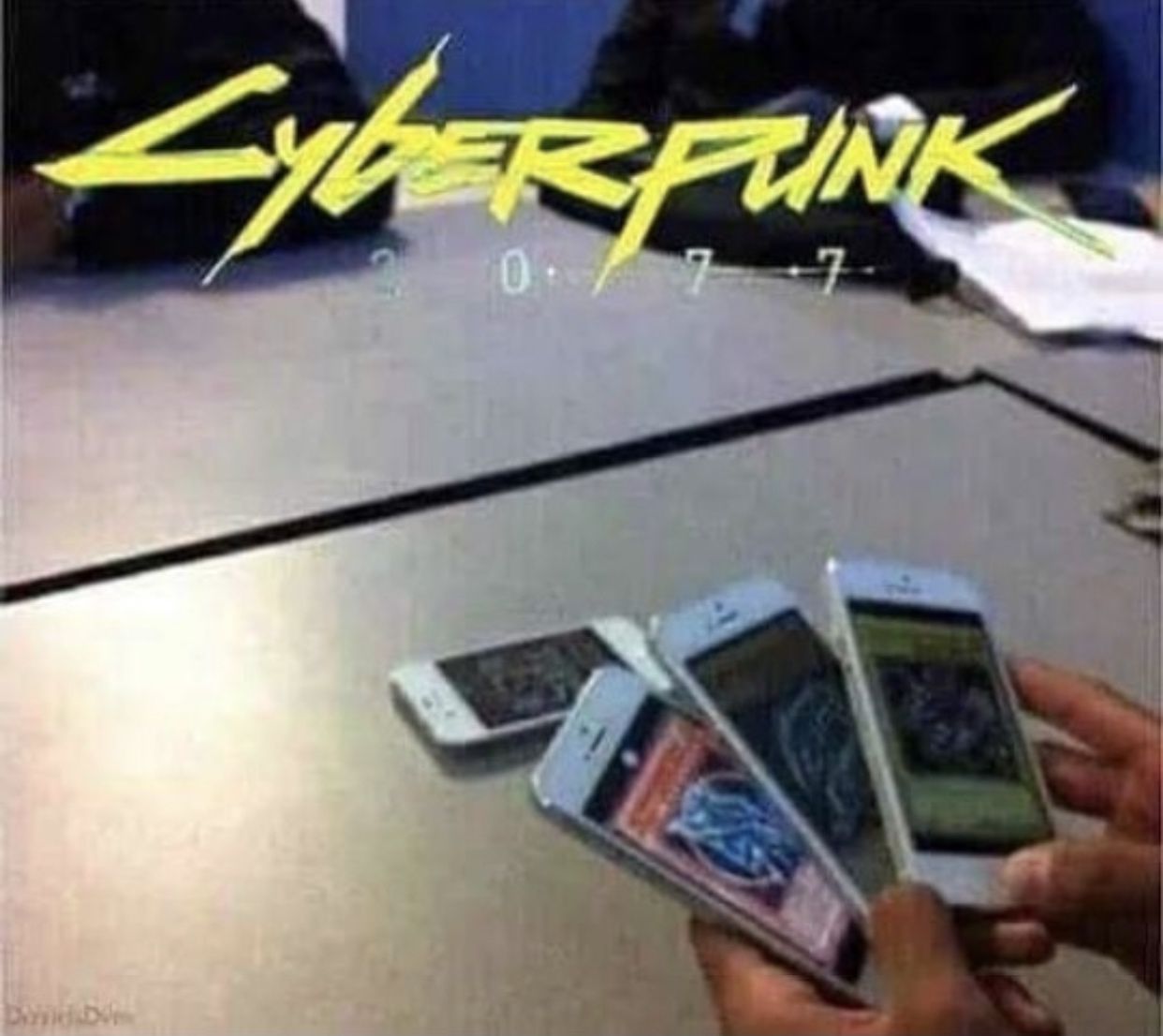 The meme is a screenshot from the 2021 film "The Matrix Resurrections" featuring a scene where a character named "The Matrix" is shown to be a "Simulation" created by a group of scientists. The image shows a group of scientists sitting at a table with their phones, and the text "Cyberpunk 2077" appears at the top of the screen. The meme is a joke about the game's poor launch and the "bug" that made it seem like players were playing the game on their phones.